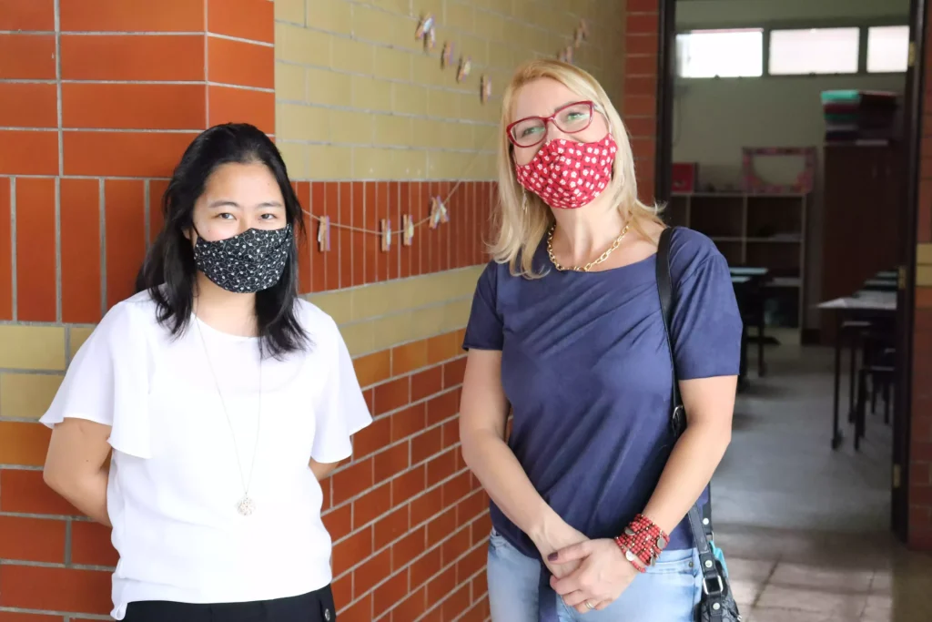 2 pessoas de mascara mostrando a época de pandemia no colégio